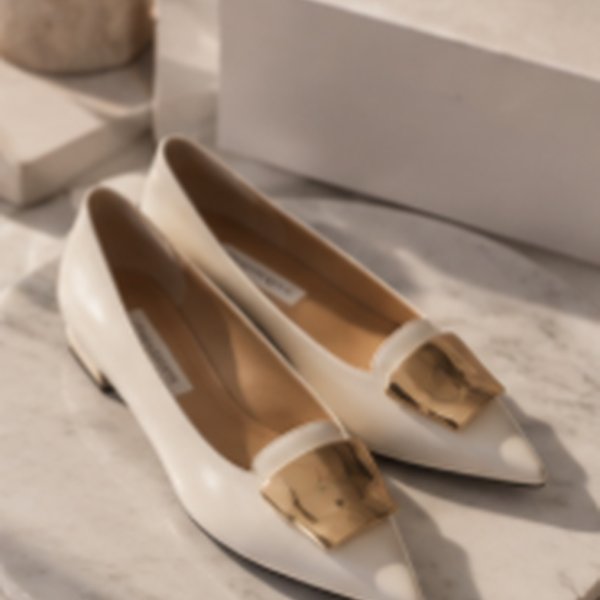 White pointed-toe pumps with a gold buckle